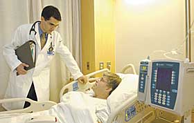 Dr. Douglas D’Andrea, a physician in the hospitalist program, visits a patient at the John Dempsey Hospital. Hospitalists oversee the care of adult inpatients and work closely with primary care providers.