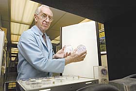 Philip Marcus, professor of molecular and cell biology, examines cell samples from the early 1950s in his lab.