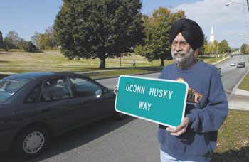 Amarjit Buttar of Vernon stands beside Route 195 with a new sign proclaiming the road UConn Husky Way.