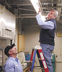 Mike Pronicki, on ladder, and John Rodriguez, both general trades workers, fix a light at the Chemistry Building.