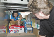 Kim Schwarz, left, operations manager at the Student Union, loads a UConn bus last fall with donations for victims of Hurricane Katrina, as Janet Freniere, transportation services administrator, looks on.