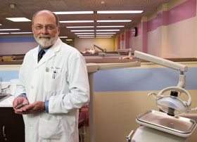 Dr. Thomas Taylor, head of Oral Rehabilitation, Biomaterials, and Skeletal Development at the Health Center, holds a model of a dental implant.