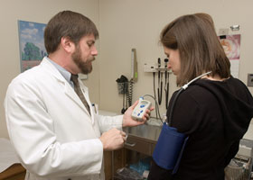 Dr. William White, chief of the Division of Hypertension and Clinical Pharmacology, demonstrates a blood pressure monitoring device at the Health Center.