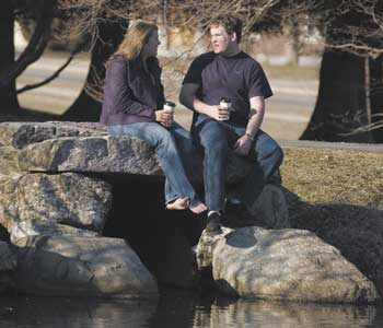 Whitney Peterson, left, and Jesse McCormick drink coffee in the sunshine, while sitting on a rock beside Mirror Lake.