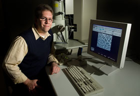 Gregory Sotzing, an associate professor of chemistry, with an electron microscope image of a fiber.