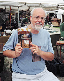 Robert Wyss, assistant professor of journalism, holds a copy of his book Brimfield Rush, at the Brimfield Antique and Collectibles Show in Massachusetts on July 12.