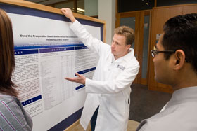 C. Michael White, associate professor of pharmacy practice, center, discusses a poster outlining a recently published study on treatment options for heart attacks with Diana Lucek, left, a pharmacy practice resident at Hartford Hospital, and Sachim Shah, a cardiovascular fellow.