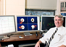 Biomedical engineer John Enderle, a professor in the Department of Electrical and Computer Engineering, with a three-screen simulation of brain control over eye movement.