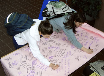 Devorah Donnell, left, and Krista Rashleigh, both sophomores, sign a poster to be sent to Virginia Tech as a gesture of sympathy after a gunman’s killing spree last week left 33 people dead at the campus in Blacksburg, Va.