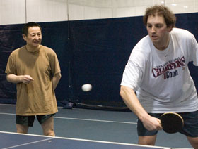 Guanhua Wang, left, an associate professor of history, is writing a book on the history of sports in China. He also coaches the University’s Ping Pong Club. Here, he instructs Doug Storace, a Ph.D. student in psychology, in proper back-hand technique.