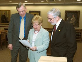 From left, President Philip E. Austin, former U.S. Rep. Nancy Johnson, and Thomas Wilsted, director of the Dodd Center, look over a document.