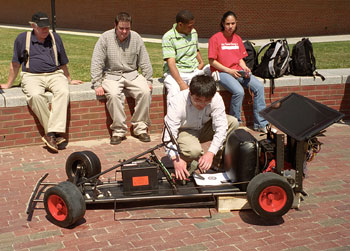 Rui Shu hooks up a voltmeter to a solar-powered car being demonstrated on Fairfield Way by Professor Martin Fox, left, and students during the EcoHusky Earth Day celebration April 23.