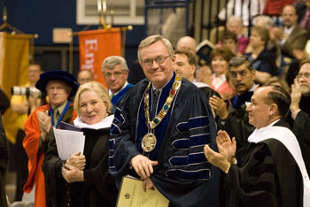President Philip E. Austin receives a standing ovation for his 11 years of service during the morning undergraduate Commencement ceremony at Gampel Pavilion. At left is speaker Fay Weldon, at right is Mark Shenkman, Class of ’65.