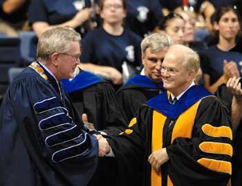 University President Philip E. Austin, left, welcomes incoming President Michael J. Hogan during Convocation at Gampel Pavilion August 24.