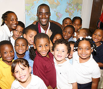 Former men's basketball player Emeka Okafor, with children at the Clark Elementary School in Hartford, after announcing his $250,000 gift to the Husky Sport program. In the back row, at left, is Lashika James, a paraprofessional at the school.