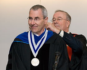 Urs Boelsterli, the first holder of the Boehringer Ingelheim Chair in Mechanistic Toxicology in the School of Pharmacy, has a medal placed around his neck by Provost Peter J. Nicholls during the installation ceremony Oct. 25.