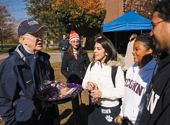 President Michael J. Hogan, left, speaks with Jeniffer Perez, Jocelyn Cerda, and Johann Delgado, all freshmen, during a Trick or Treat session outside Gulley Hall.