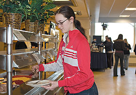 Loraine Stevens, a freshman majoring in economics, scoops food onto her plate in Whitney Dining Hall. Whitney has been experimenting with eliminating trays from the dining hall to help reduce waste.