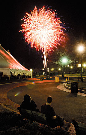 Students watch the fireworks Saturday evening, from a bench along Fairfield Way.