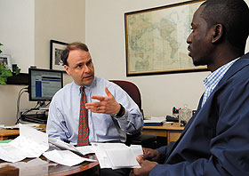 Professor Peter Kochenburger, executive director of the Insurance Law Center, left, meets with Nasser Sserunjogi, an Ll.M. student, in his office at the Law School.
