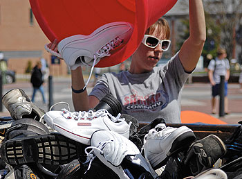 Lorelle Schaub, a junior, pours a tub of used sneakers into a dumpster for recycling during the EcoHusky Earth Day Spring Fling, held on Fairfield Way April 22. 