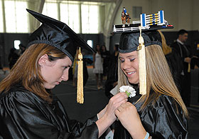 Amanda Morris helps Amy Kriwitsky before the College of Agriculture and Natural Resources ceremony at the Field House.