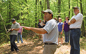 Art Talmage, owner of Cranberry Hill Farm in Ashford, leads students taking an environmental journalism class on a tour of the farm. At right is Professor Robert Wyss, who developed the course. 