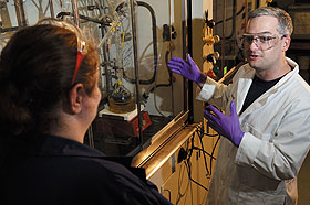 Justin Fair discusses his research with Christine Cardillo in a lab in the Chemistry Building. Both are Ph.D. students.