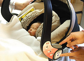 Newborn Lucy Doyle-Kusy naps, as her parents prepare her safety seat for the ride home from Dempsey Hospital. The sticker her parents affixed to the car seat will help first responders in the event of an emergency.