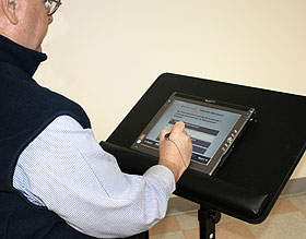 A patient operates the medication management software using a touch screen to respond to questions.