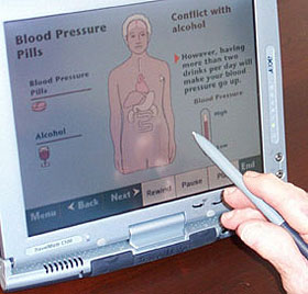 A partient uses a stylus on the touch screen.