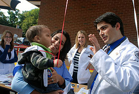 Rod Ghassemzadeh, right, a second year medical student and site leader at the C-Town Supermarket in Hartford, entertains one of the younger participants during the community service day.