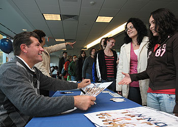 Geno Auriemma, head coach of the UConn Women's Basketball team, signs autographs for participants in the sports health program for young female athletes at the Health Center.