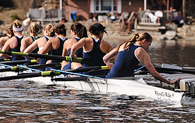 Members of the Women’s Rowing Team push off from the dock at the boathouse on Coventry Lake in their new racing shell, named in honor of retired psychology professor Sam Witryol.