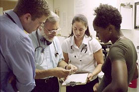 Image: Students and supervising physician consult with a patient.